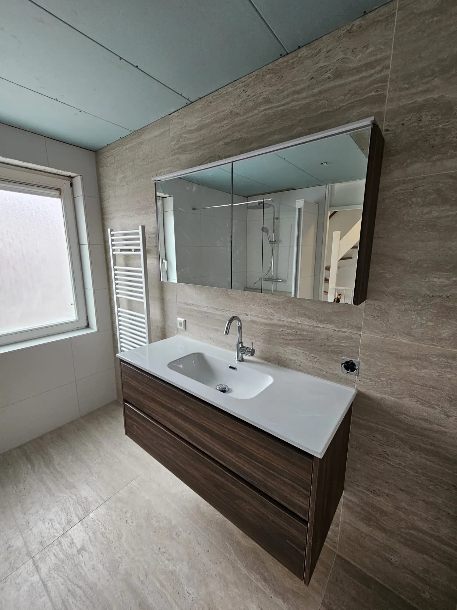 Badkamer renovatie met wastafelmeubel in houtlook en travertin tegel