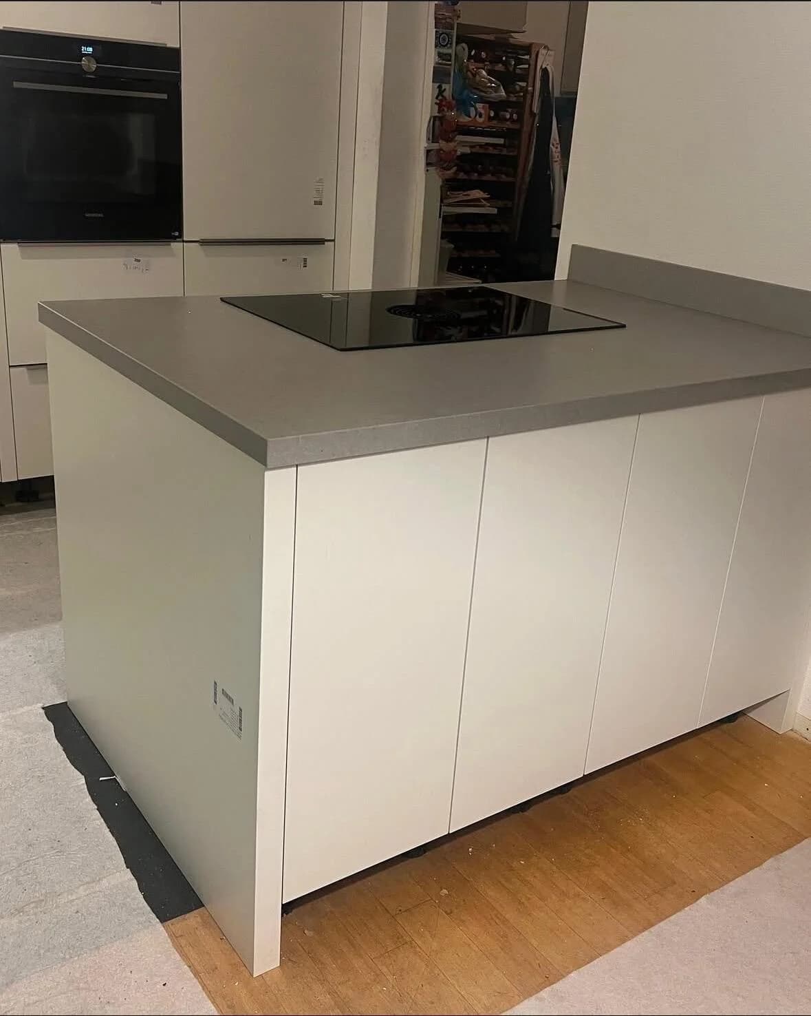 Witte keuken met kookeiland en grijs werkblad