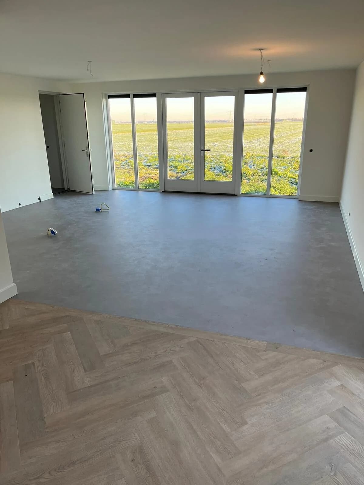 Combinatievloer visgraat en betonlook in woonkamer met panoramische ramen
