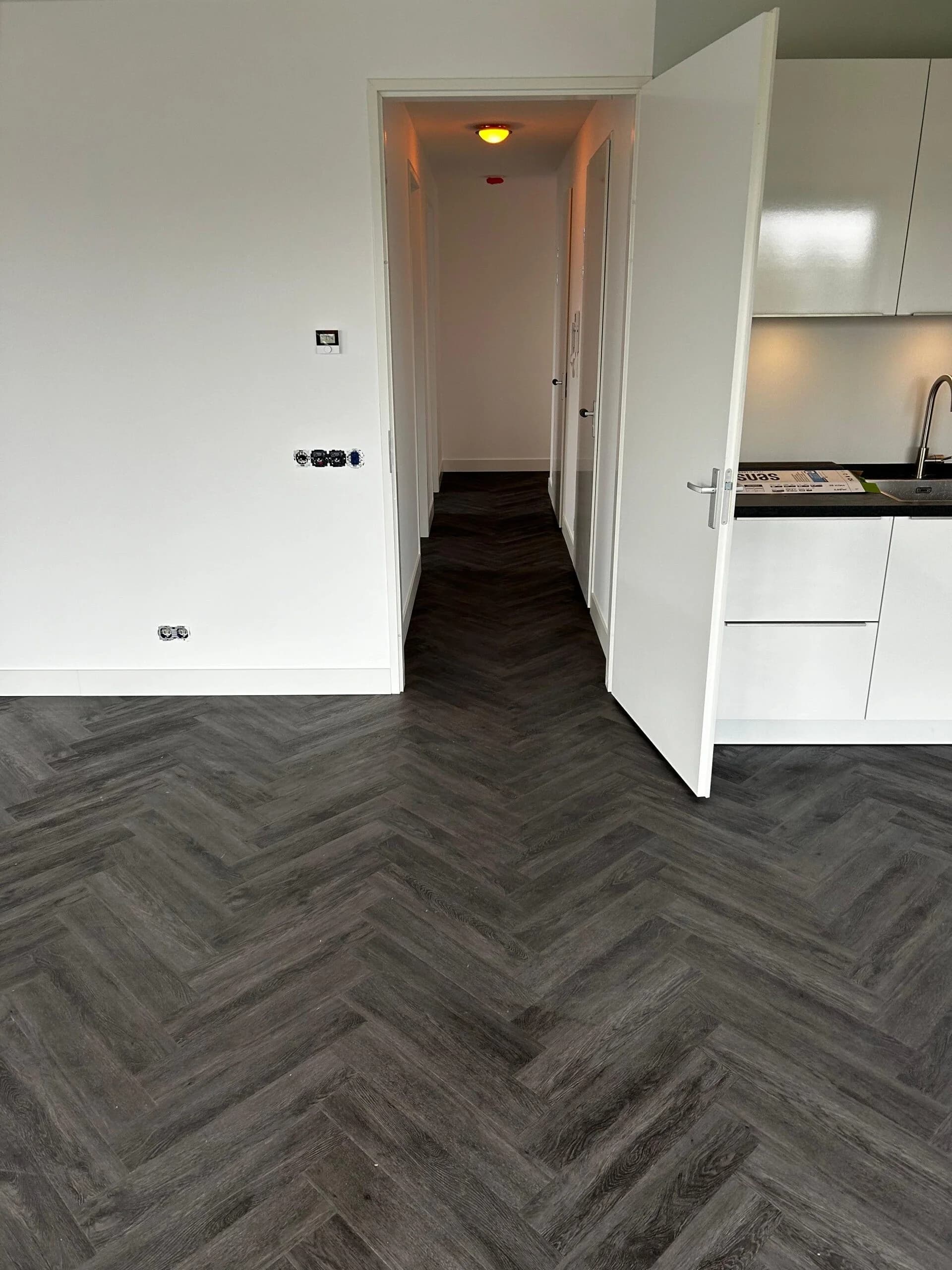 Donkergrijze visgraat PVC vloer in woonkamer met keuken