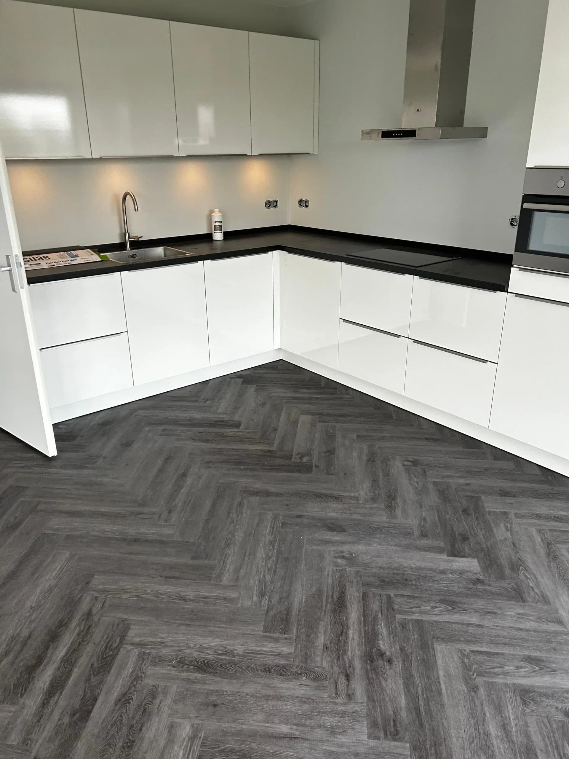 Grijze visgraat PVC vloer met witte keuken
