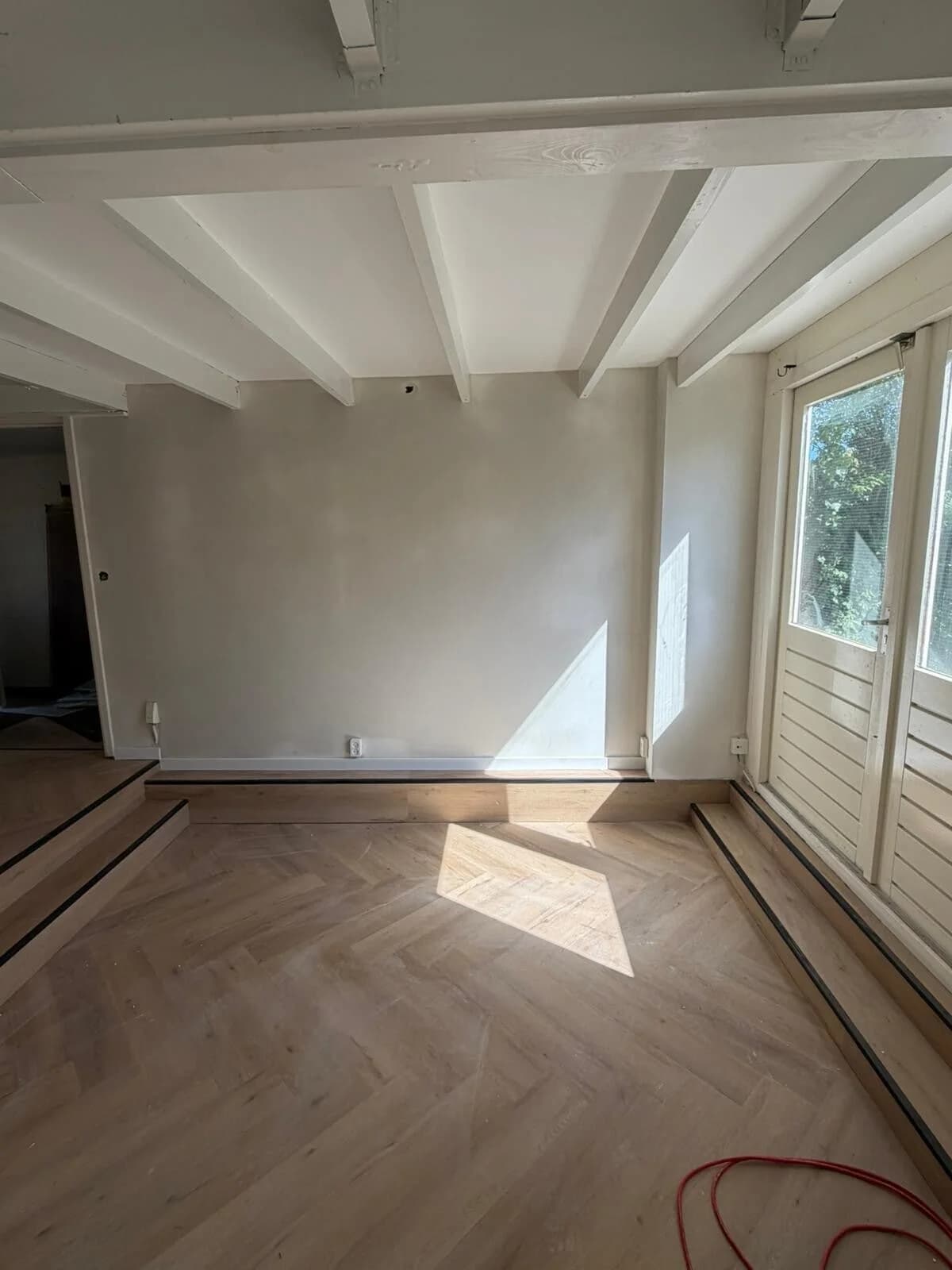 Lichte visgraat PVC vloer in woonkamer met balkenplafond