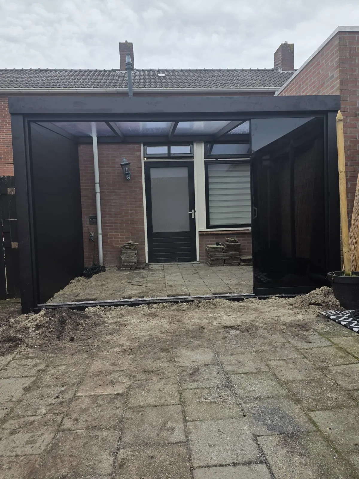 Voorzijde van de antraciet overkapping met dichte zijwand in een tuin in Alkmaar