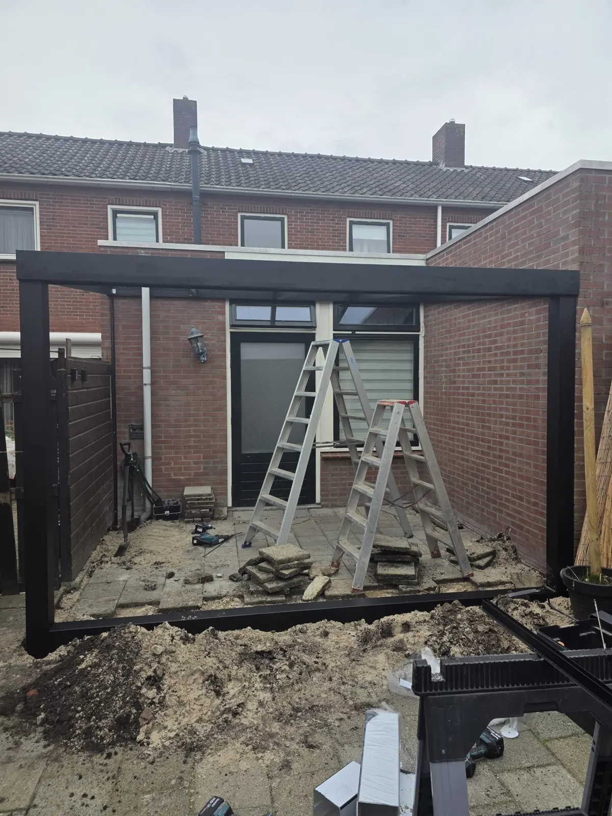 Antraciet frame van de overkapping tijdens de montage in een achtertuin in Alkmaar
