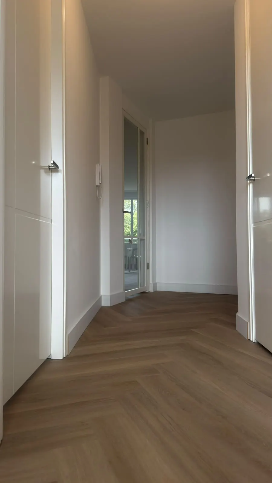Hal met nieuwe visgraatvloer en witte binnendeuren na de appartementrenovatie in Alkmaar