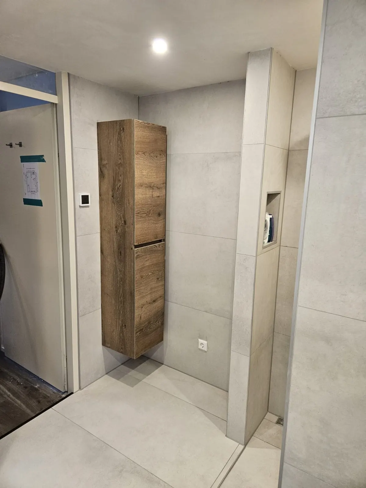 Hoge hangende houten kast naast de douche in een badkamer in Castricum