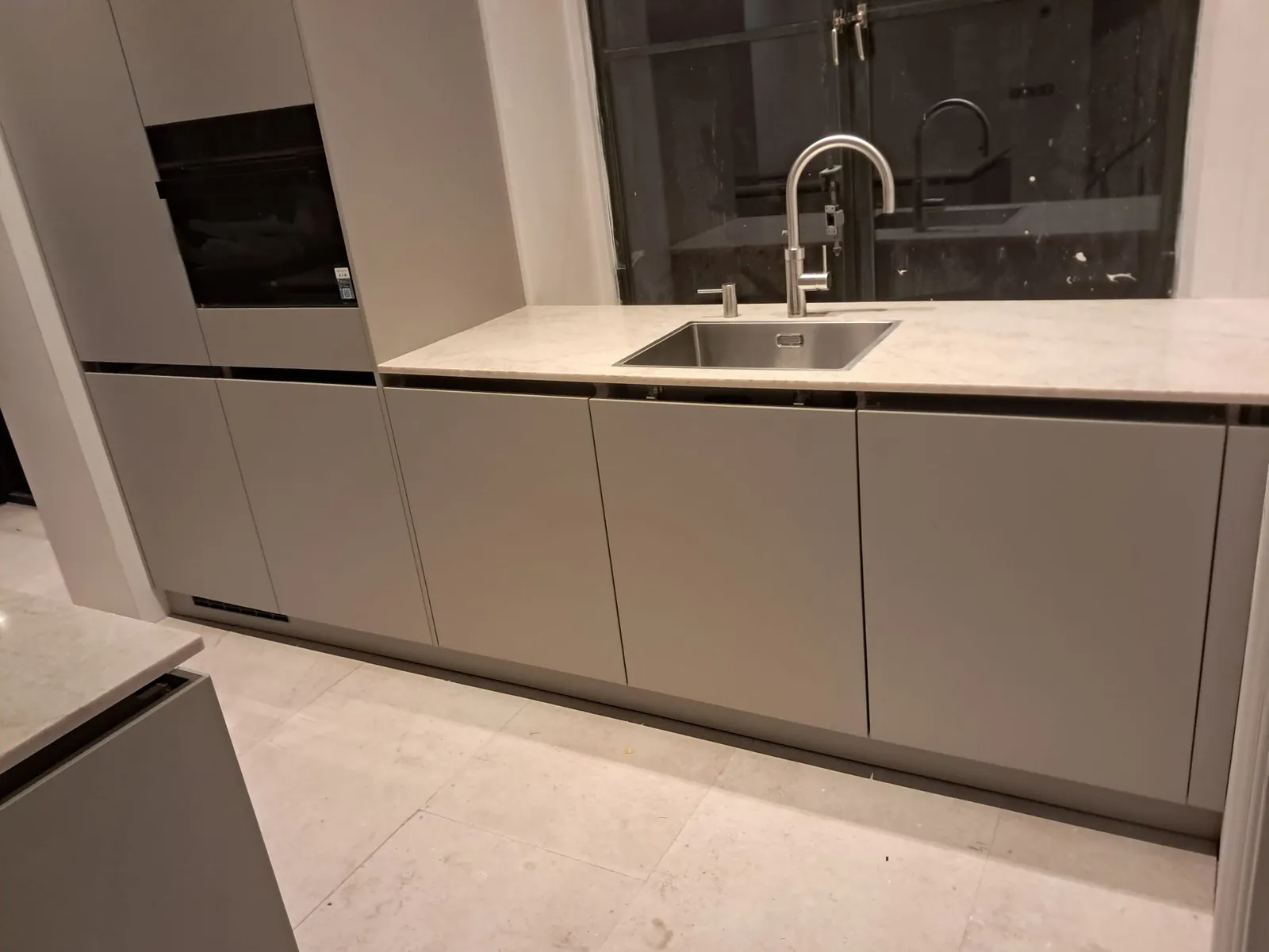 Taupe greeploze keukenwand met spoelbak en marmerlook werkblad, keukenmontage in Bergen