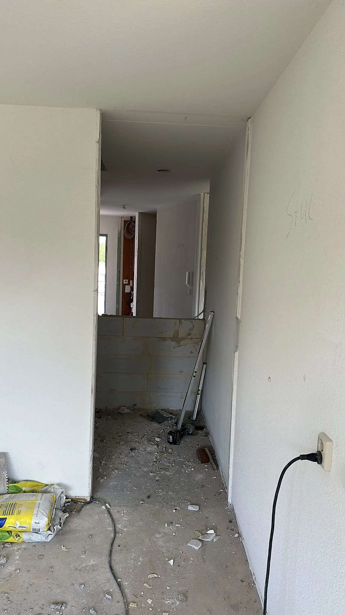 Hal in sloopfase met meterkast zichtbaar en gestripte vloer in Heerhugowaard